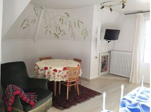 A cozy room with a round table, a green armchair, and a patterned rug.