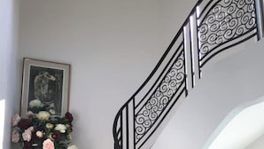 A staircase with a black metal railing and a vase of flowers on a wooden dresser. - F1 overlooking Lac d'Allier and park, 5' from thermal baths (Vichy)