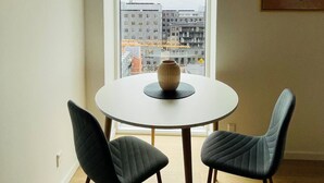 A dining area with a round table, two chairs, a vase, and a city view through a large window. - City Apartment in Copenhagen with 1 bedrooms sleeps 2 (Copenhagen)