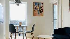 A modern living room with a dark blue sofa, two chairs, a round table, and a painting on the wall. - City Apartment in Copenhagen with 1 bedrooms sleeps 2 (Copenhagen)