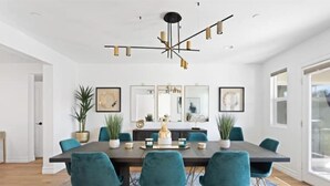 Une salle à manger moderne avec une table en bois foncé, des chaises de couleur turquoise et un lustre original.
