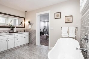 Une salle de bain moderne avec une baignoire sur pieds, un grand miroir et un meuble-lavabo.