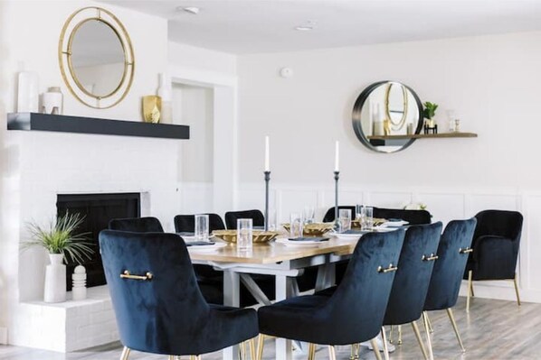 Une salle à manger avec une table ronde, des chaises bleu foncé et une cheminée.