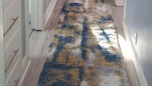 Ein Flur mit einem gemusterten Teppich, einer Deckenleuchte und einer Tür links.