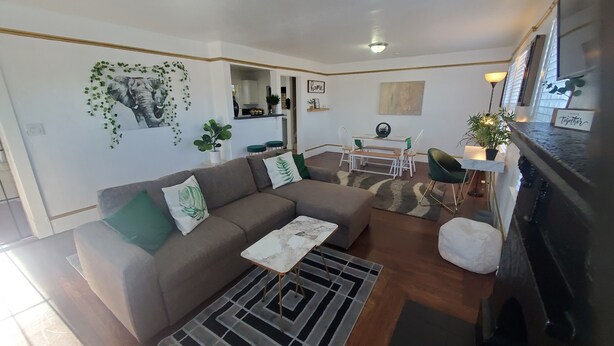 A living room with a sofa, a coffee table, a rug, and a fireplace. There is a dining area with a table and chairs. - The Modern Family Getaway (Oakland)