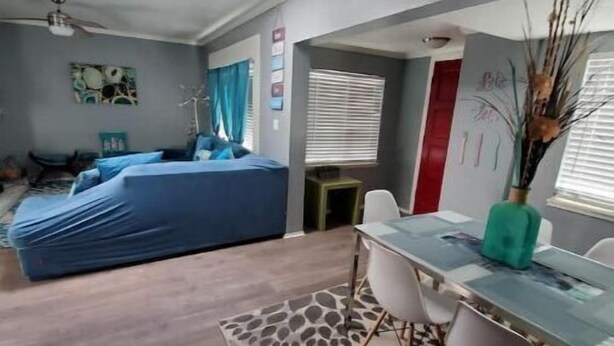 Ein modernes Wohnzimmer mit einer Sofagarnitur, einem Esstisch mit Stühlen und einem Deckenventilator.