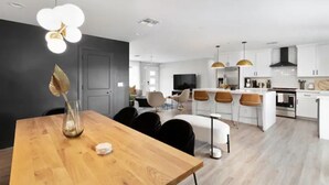 Une cuisine moderne avec des meubles blancs, un îlot central doté de tabourets et un éclairage suspendu.