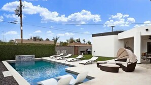 Une piscine avec des chaises longues et un espace de détente abrité.