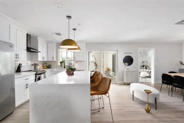 A modern kitchen with white cabinetry, a central island, and a dining area with a round table and chairs.