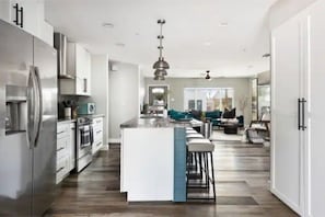 Una cocina moderna con una isla central, electrodomésticos de acero inoxidable y una zona con taburetes de bar.