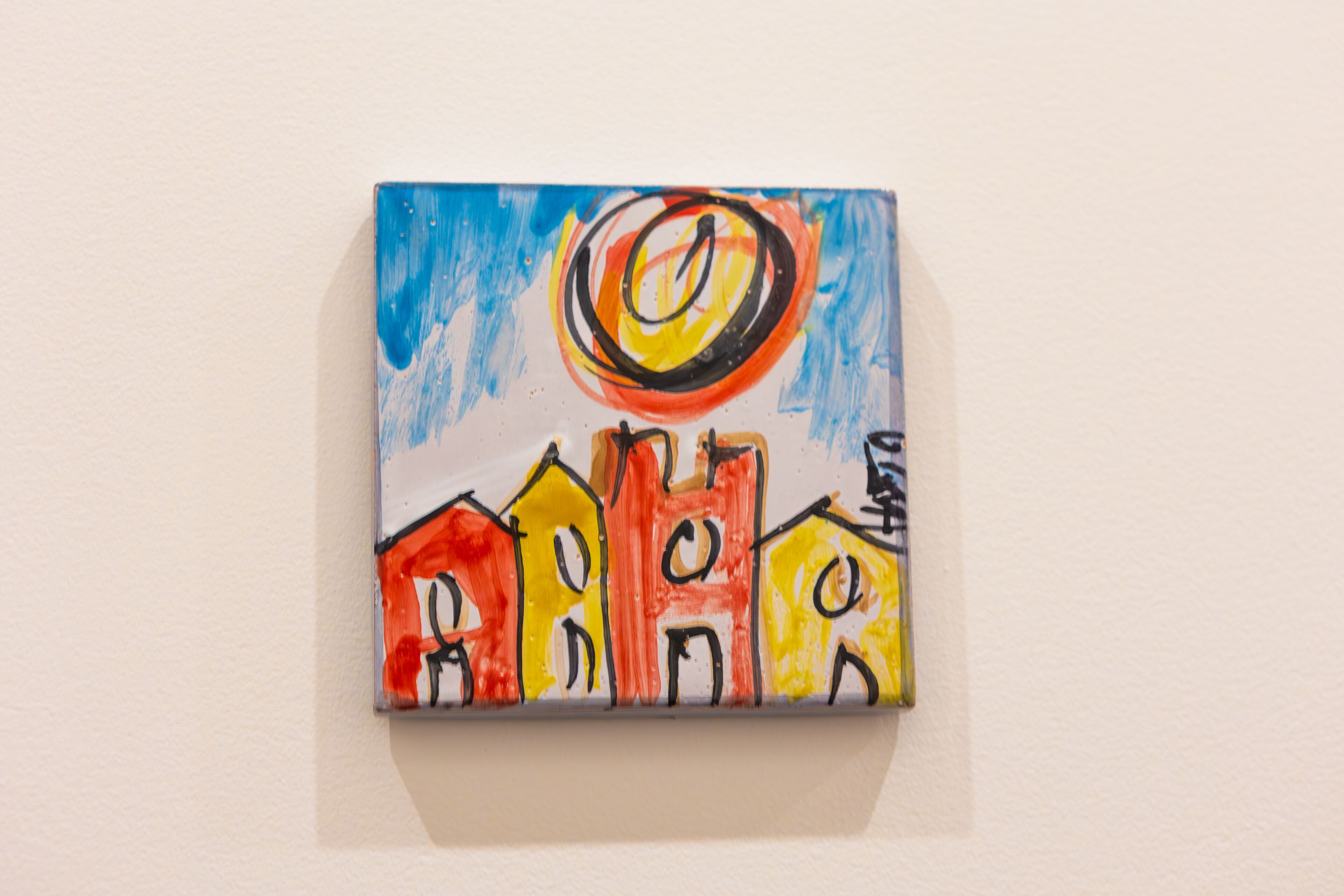Une petite peinture colorée représentant des maisons sur un mur.