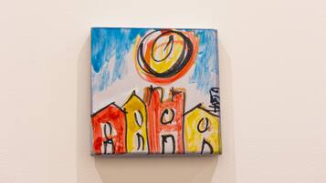 Une petite peinture colorée représentant des maisons sur un mur.