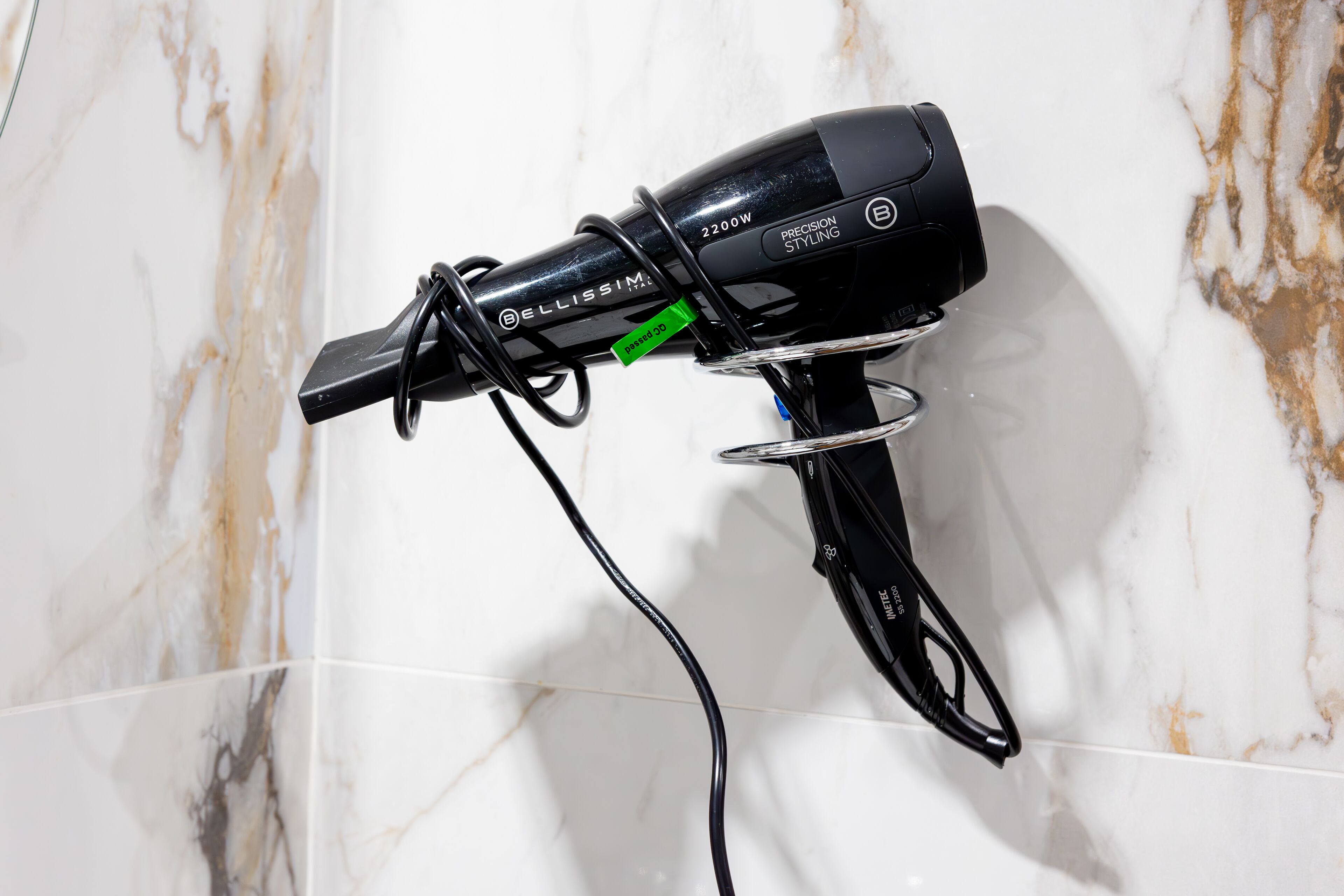 Un secador de pelo montado en una pared con fondo de mármol.