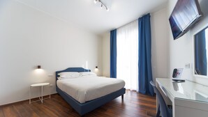 A modern bedroom with a bed, a desk, and a flat-screen TV.