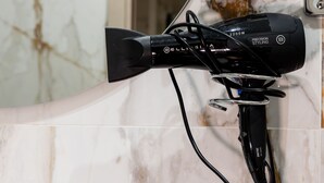 A hairdryer with a cord and a power cord plugged into a wall socket.
