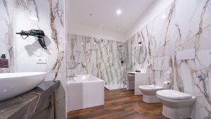 A modern bathroom with a large white sink, a freestanding bathtub, two toilets, and a bidet.
