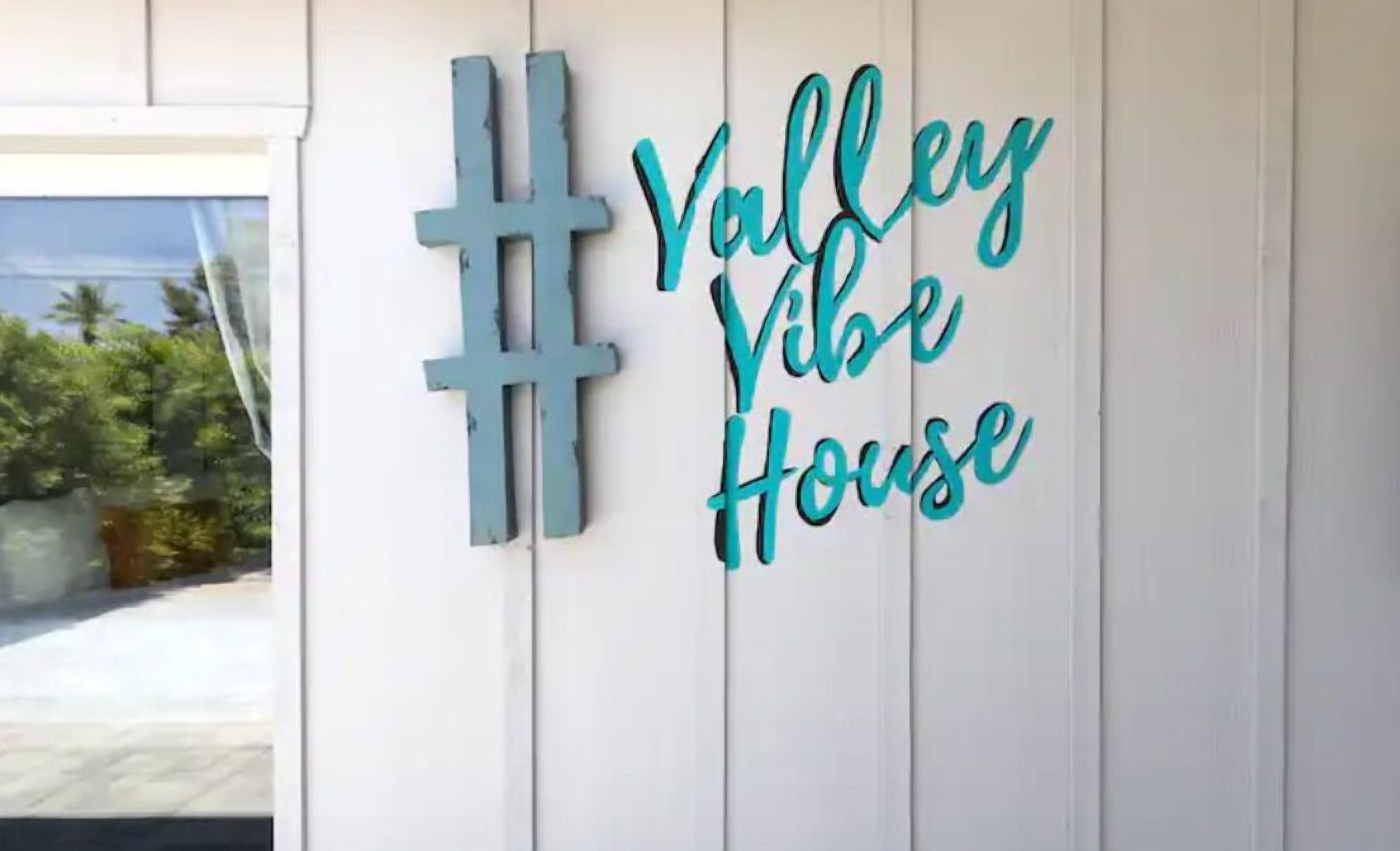 A wall with a sign that reads "Valley Vibe House" and a large hashtag symbol.