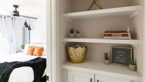 Une chambre à coucher avec un lit, un ventilateur de plafond et une fenêtre avec des rideaux.