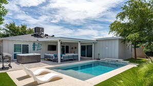 Une maison moderne dotée d’une piscine, d’un espace salon extérieur et d’un jacuzzi.