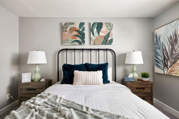 A bedroom with a bed, two nightstands, two wall-mounted lamps, and two framed artworks. - Heated Pool, Lavish Yard! - The Desert Wanderer (Scottsdale)