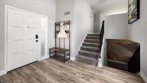 A modern interior with a wooden floor, a staircase, a white door, and a hanging lamp. - Heated Pool, Lavish Yard! - The Desert Wanderer (Scottsdale)