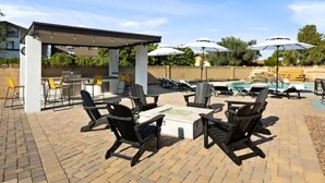 An outdoor patio with black lounge chairs, a fire pit, and umbrellas. - Heated Pool, Lavish Yard! - The Desert Wanderer (Scottsdale)