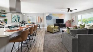 A modern living room with a grey sofa, a TV, and a dining area with chairs and a table. - Heated Pool, Lavish Yard! - The Desert Wanderer (Scottsdale)