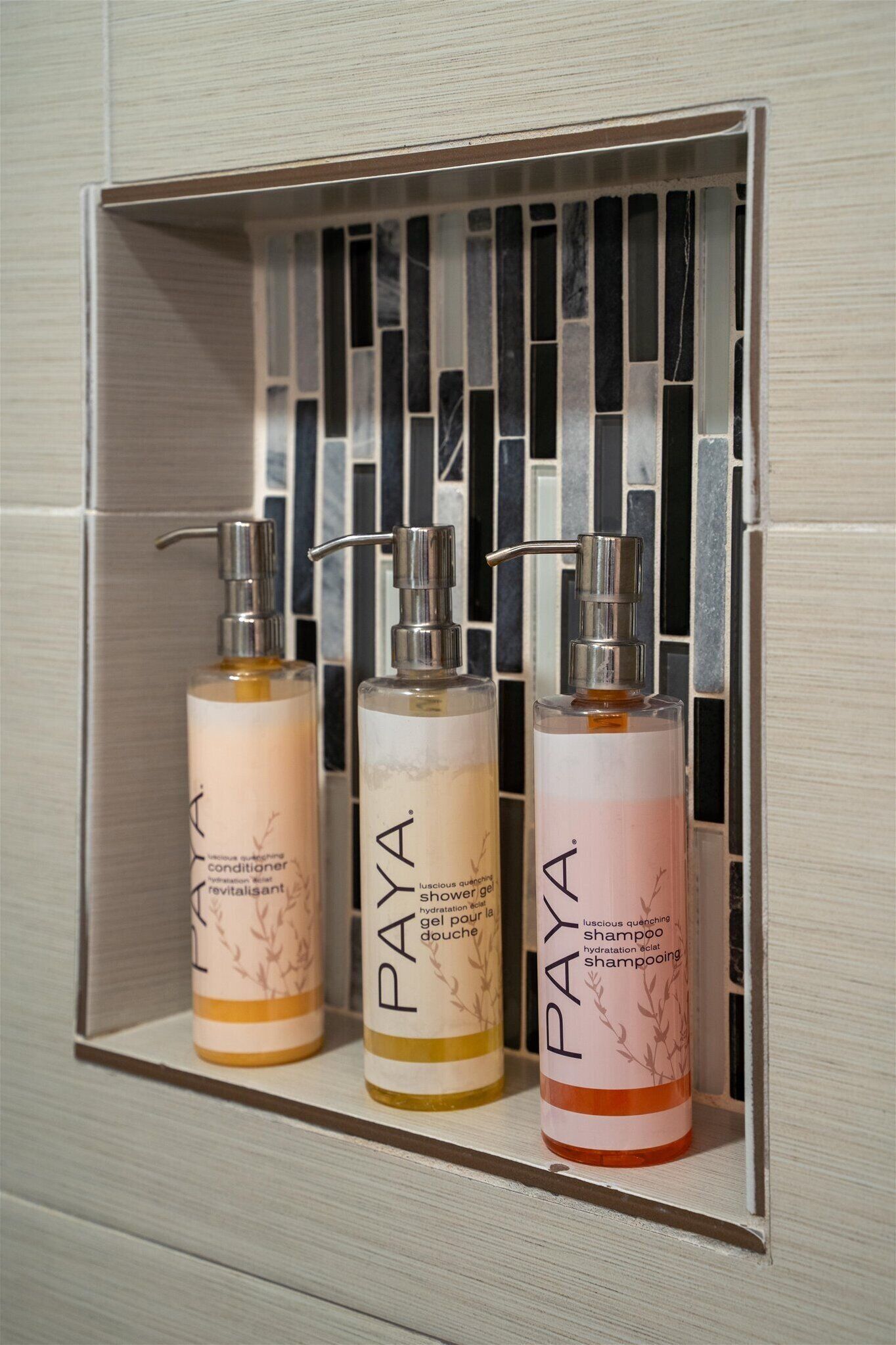 Three bottles of Paya hair care products in a bathroom shelf.