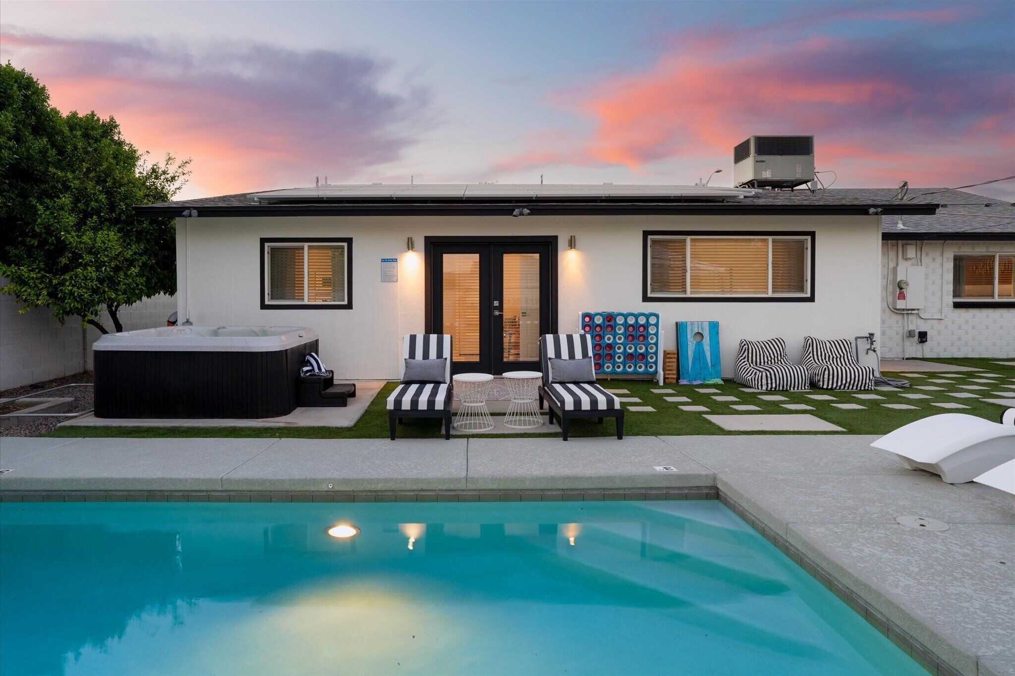 Una casa moderna con piscina, mobiliario exterior y vistas al atardecer.