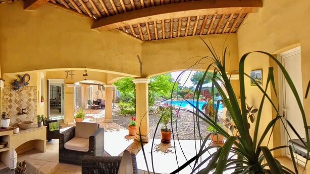 A covered patio with a fireplace, outdoor seating, and a view of a swimming pool. - Rental Residence Peylon with swimming pool terrace garden patio in a quiet area (Flayosc)