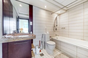 Une salle de bain moderne avec un grand miroir, un lavabo, des toilettes et une baignoire.