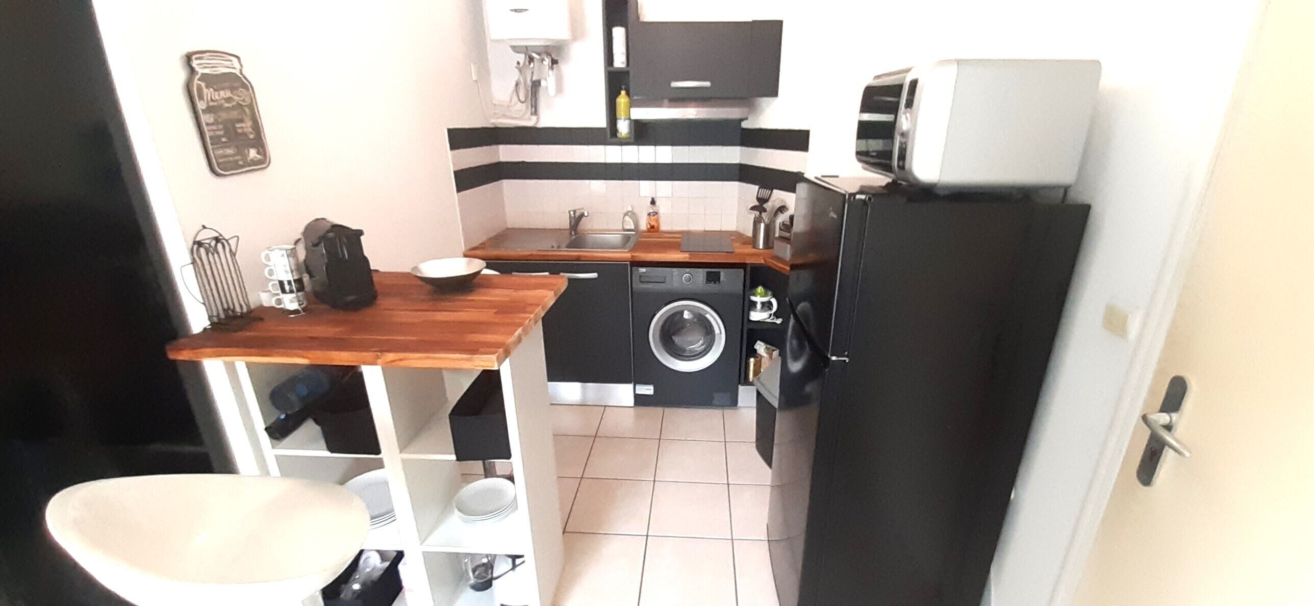 Ett litet kök med tvättmaskin, diskho och mikrovågsugn.