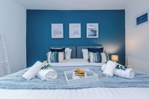 Une chambre à coucher avec un grand lit, des murs bleus et trois tableaux encadrés accrochés au mur.