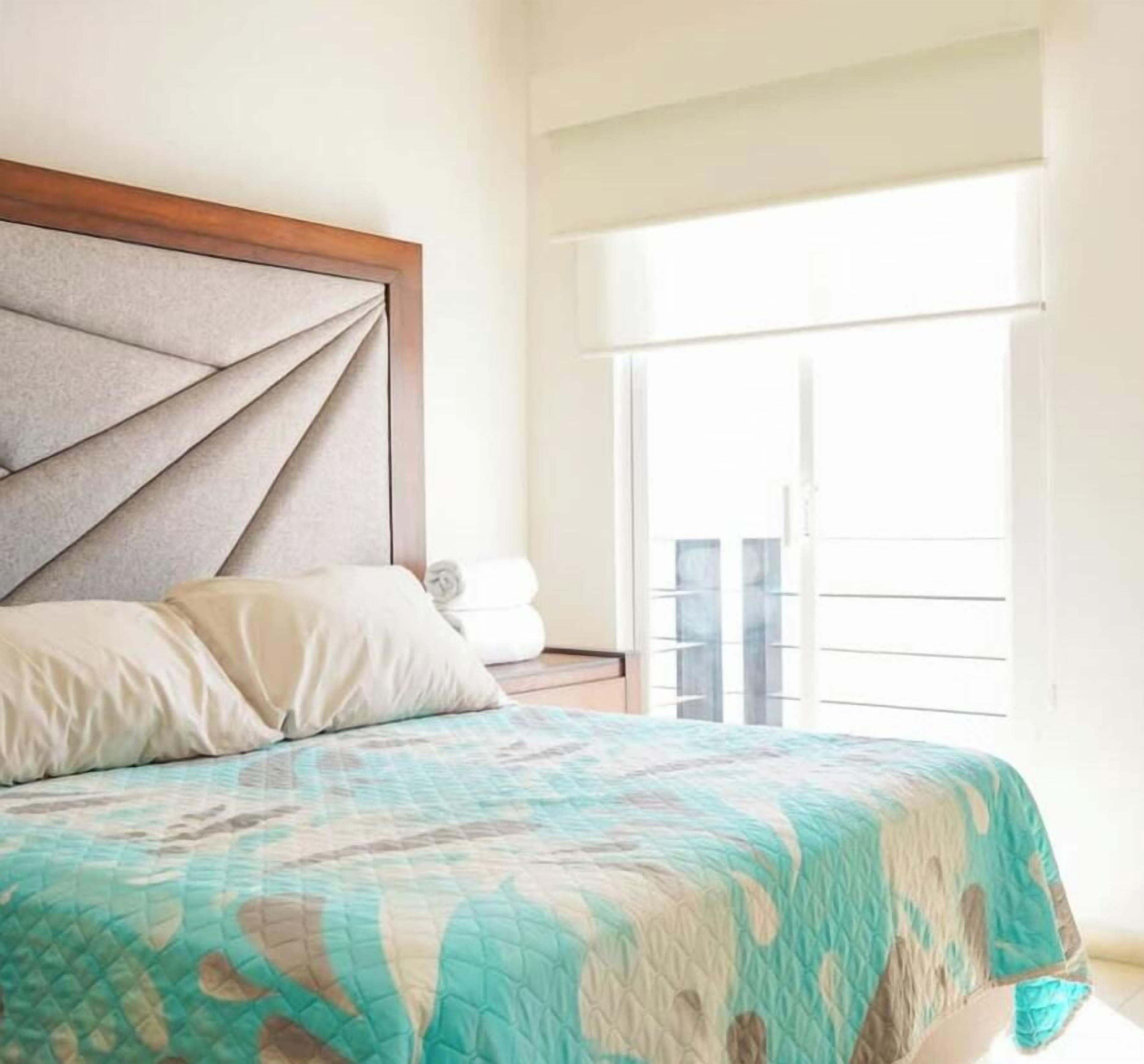 Une chambre à coucher avec un lit, une fenêtre avec des stores et une vue sur l’extérieur.