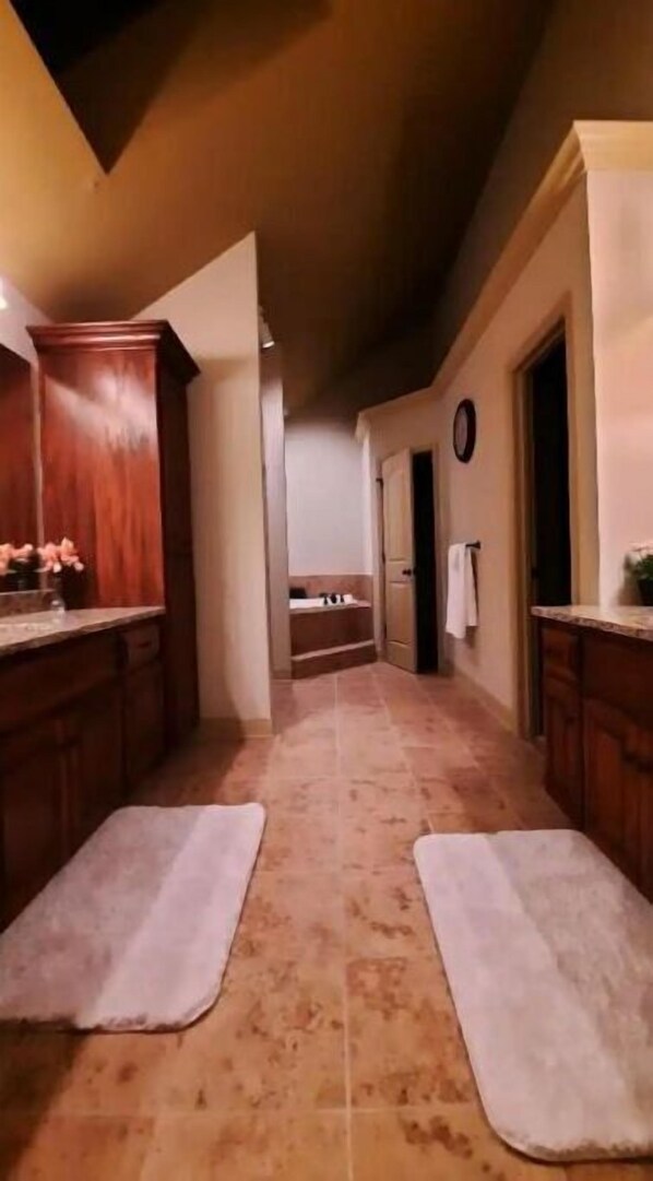 A narrow hallway with a kitchen area on one side and a bathroom on the other, featuring a tiled floor and wooden cabinets. - Peaceful Oasis (Shawnee)