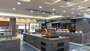 A modern kitchen area with a central island, overhead lighting, and a visible sign for 'Café'. - Galini Private Pool Suites with Sea View (Chania)