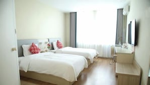 Ein Hotelzimmer mit zwei Betten, einem Nachttisch, einem Spiegel und einem Fenster mit Vorhängen.