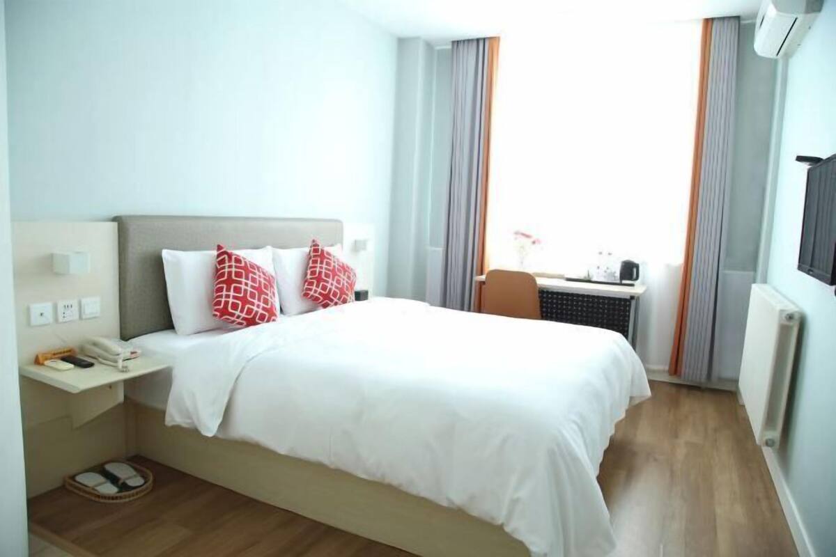 Une chambre d’hôtel équipée d’un lit, d’un bureau, d’une chaise, d’un téléphone et d’un radiateur.