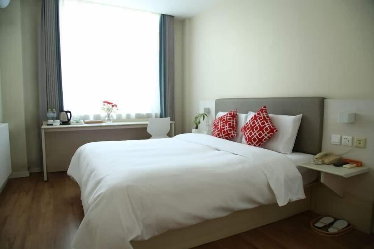 Une chambre d’hôtel avec un lit, une table de chevet et une fenêtre avec des rideaux.
