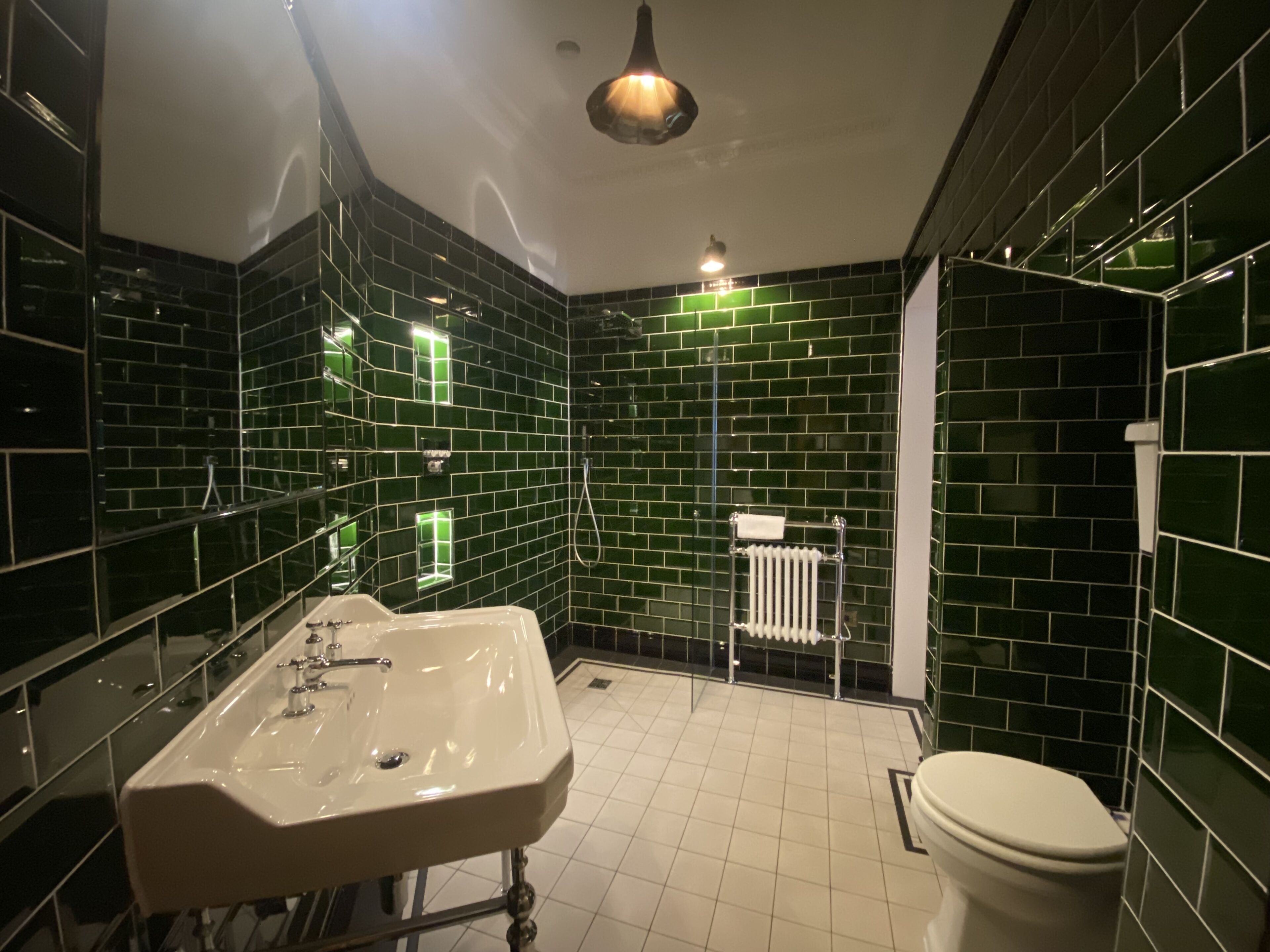 A bathroom with green-tiled walls, a white sink, and a toilet.