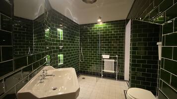 A bathroom with green-tiled walls, a white sink, and a toilet.
