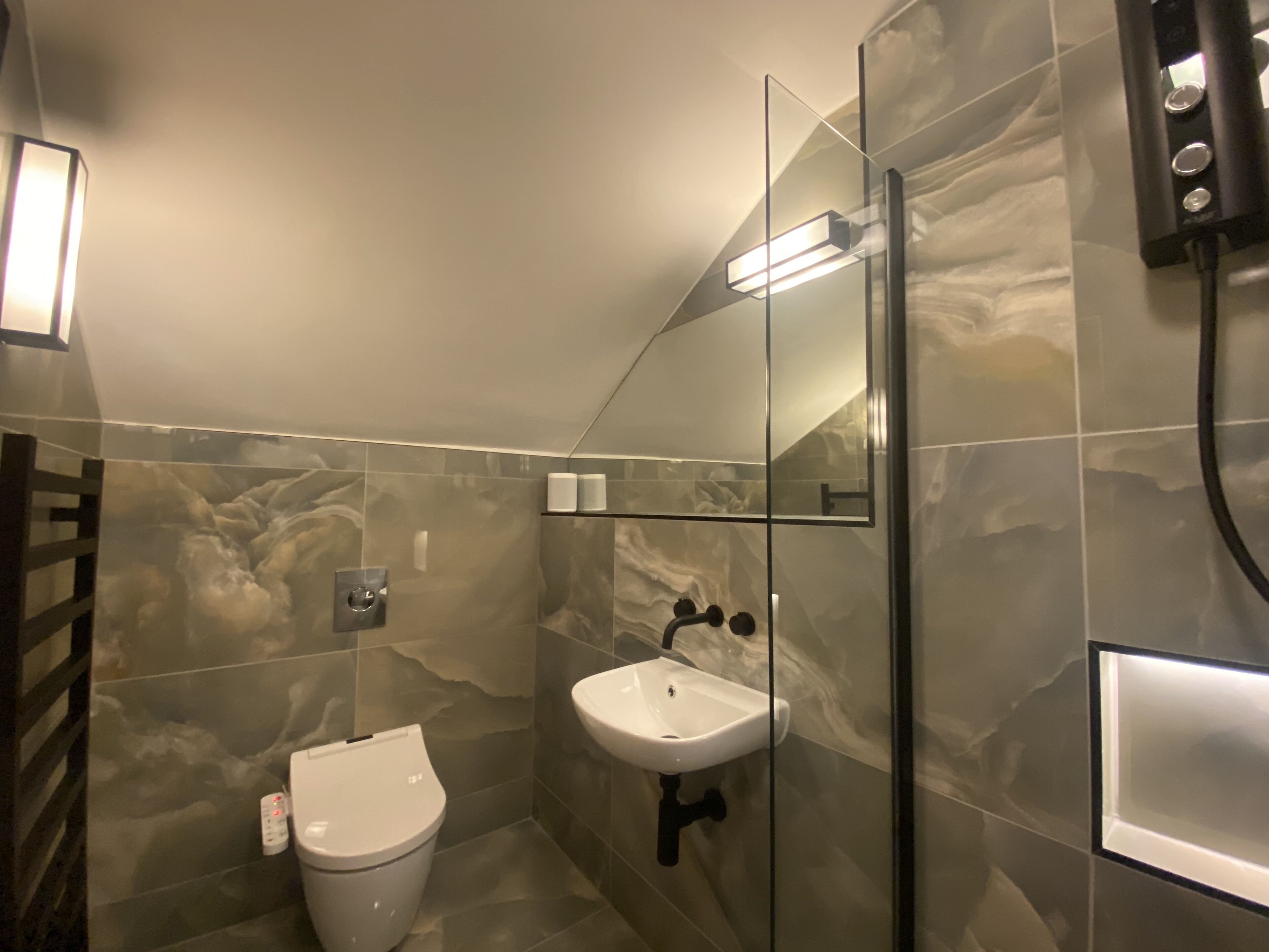 A modern bathroom with a toilet, sink, and glass shower enclosure.