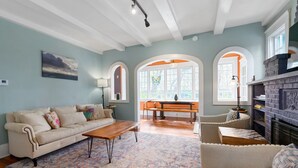 A living room with a sofa, coffee table, and armchairs, a fireplace, and a view through arched windows. - 8 Park l Dog Friendly l Outdoor Oasis l Mins to Beach (St. Augustine)