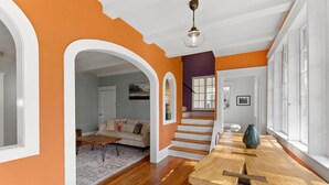 A spacious living room with a wooden floor, a large dining table, and a staircase leading to another level. - 8 Park l Dog Friendly l Outdoor Oasis l Mins to Beach (St. Augustine)