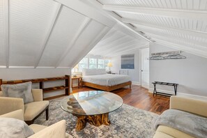 Une chambre avec un grand lit, une table ronde en verre et un banc en bois.