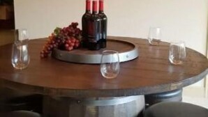 Ein runder Esstisch mit sechs Hockern, einer Flasche Wein in der Mitte und einer Obstschale.