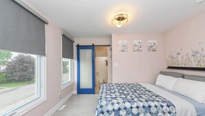A bedroom with a bed, a window with blinds, a door leading to a bathroom, and wall art. - 5 Minutes Walk to Niagara Falls (Niagara Falls)