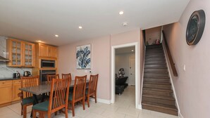 A kitchen with wooden cabinets, a dining table with chairs, a painting on the wall, and a staircase leading to another room. - 5 Minutes Walk to Niagara Falls (Niagara Falls)
