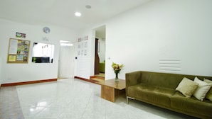 A reception area with a green sofa, a wooden coffee table, and a vase of flowers. There are bulletin boards on the wall and a door leading to another room. - Poblado Park Guest House (Medellín)