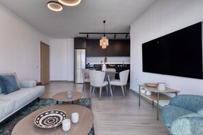 A modern living room with a sofa, a coffee table, and a dining area with chairs and a table.